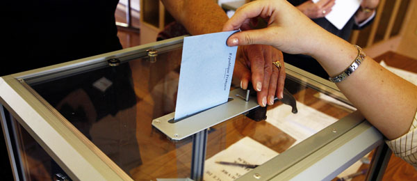 Una persona introduce una papeleta en una urna