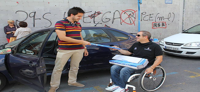 Un voluntario de COCEMFE Alicante entrega información a un conductor