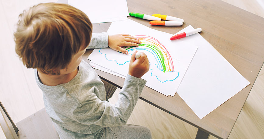 Un niño en casa dibujando un arcoiris