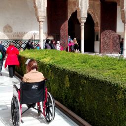 Una mujer con discapacidad visita la Alhambra de Granada en un turno de vacaciones de COCEMFE