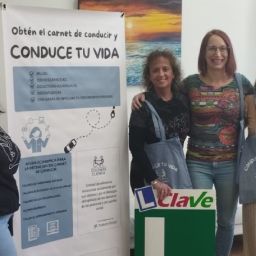 Mujeres participantes del programa Conduce tu Vida junto al roll-up de COCEMFE Cuenca en una autoescuela colaboradora