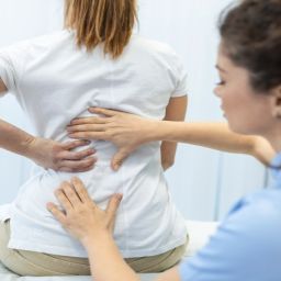Atención a personas con artritis y espondiloartritis Profesional de la salud atendiendo a una persona con dolor de espalda por artritis o espondiloartritis.