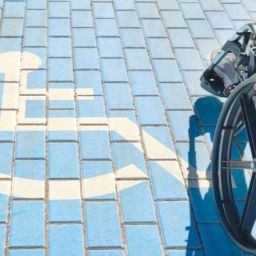 Accesibilidad y derechos de las personas con discapacidad. Persona en silla de ruedas sobre un pavimento azul con el símbolo de accesibilidad, representando inclusión y derechos.