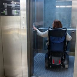 Mujer en silla de ruedas entra en un ascensor accesible, simbolizando la importancia de la accesibilidad y la vida independiente