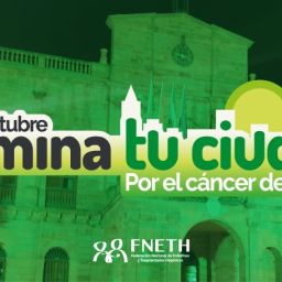 Edificio iluminado de verde con el lema de la campaña de FNETH por el cáncer de hígado.