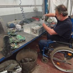 Persona con discapacidad trabajando en taller inclusivo de COCEMFE Castelló Hombre en silla de ruedas trabajando con componentes electrónicos en un taller adaptado de COCEMFE Castelló dentro del proyecto Sumando capacidades.