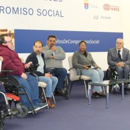 Personas participantes en una mesa de diálogo durante el 40º aniversario de COCEMFE Sevilla, con panel institucional de fondo.