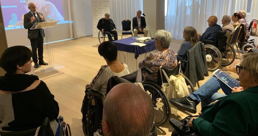 Ponente habla ante un público diverso, con varias personas en silla de ruedas, durante una jornada sobre inclusión.