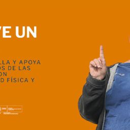 Hombre sonriente levantando el dedo índice frente a un fondo naranja en la campaña “Mueve un Dedo” de COCEMFE.