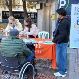 Mesa informativa de COCEMFE Castellón con personas usuarias y voluntariado en la plaza Borrull de Castelló de la Plana.