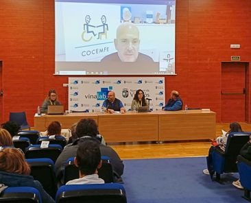 Asistentes y mesa institucional durante la jornada MIPI de COCEMFE celebrada en Vinaròs, con ponencia proyectada en pantalla.