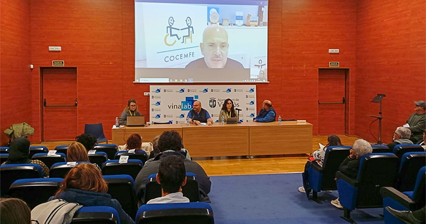 Asistentes y mesa institucional durante la jornada MIPI de COCEMFE celebrada en Vinaròs, con ponencia proyectada en pantalla.