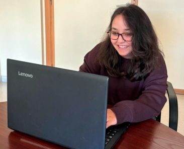 Joven con discapacidad utilizando un ordenador portátil en un entorno de trabajo, símbolo del acceso al empleo inclusivo promovido por COGAMI en Galicia.