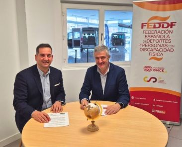 Firma del acuerdo entre la FEDDF y Rehatrans Representantes de la FEDDF y Rehatrans firmando un acuerdo de colaboración en una sala con vehículos adaptados al fondo.