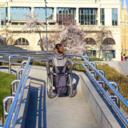 Mujer en silla de ruedas utilizando una rampa accesible en un entorno urbano.