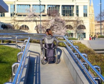 Mujer en silla de ruedas utilizando una rampa accesible en un entorno urbano.