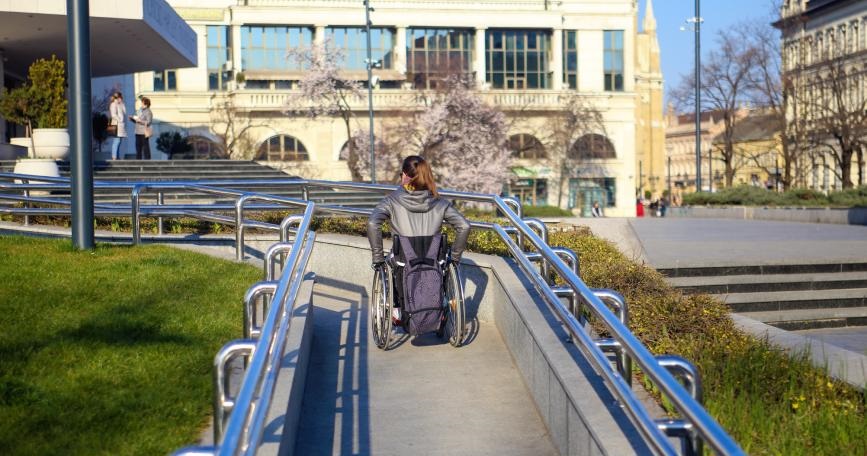 Mujer en silla de ruedas utilizando una rampa accesible en un entorno urbano.