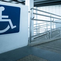 Rampa accesible con barandillas y señal de movilidad reducida en un edificio.