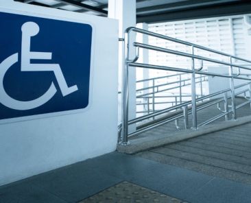 Rampa accesible con barandillas y señal de movilidad reducida en un edificio.