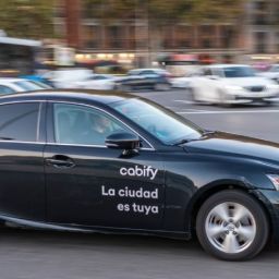 Coche de Cabify circulando por una avenida de Madrid con el logotipo de la empresa en la puerta.
