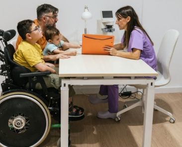 Profesional asesora a una familia con menores con discapacidad en un servicio de mediación educativa inclusiva.