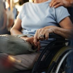 Persona con enfermedad neuromuscular usuaria de silla de ruedas acompañada por otra persona en un entorno cotidiano.