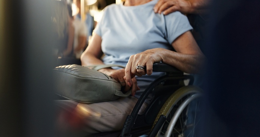 Persona con enfermedad neuromuscular usuaria de silla de ruedas acompañada por otra persona en un entorno cotidiano.