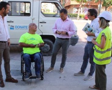 Personas evaluando la accesibilidad de un espacio urbano junto a una persona usuaria de silla de ruedas.