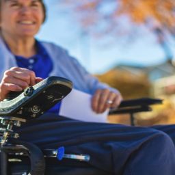 Persona usuaria de silla de ruedas eléctrica en un entorno urbano, imagen representativa de una campaña de sensibilización sobre la esclerosis múltiple.