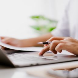 Persona revisa documentación y realiza una solicitud online en un portátil para las Ayudas Sociales AMIFP 2025.