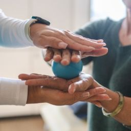 Dos personas realizan un ejercicio con una pelota terapéutica durante una sesión de apoyo profesional para personas con artritis.