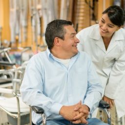 Persona usuaria de silla de ruedas recibe asesoramiento profesional sobre material ortoprotésico en un entorno sanitario accesible.