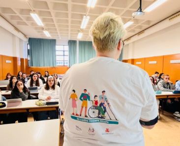 Ponente de COCEMFE Alicante imparte una charla a estudiantes de Trabajo Social en un aula de la Universidad de Alicante.