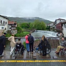Grupo de personas con discapacidad observando un río desde un puente accesible durante el Programa de Vacaciones de COCEMFE