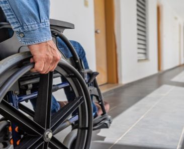 Accesibilidad en edificios residenciales Persona usuaria de silla de ruedas desplazándose por el interior de un edificio residencial, representando la necesidad de accesibilidad en viviendas.