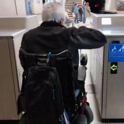 Acceso accesible en estación de Euskotren Persona usuaria de silla de ruedas pasando por una canceladora accesible en una estación de tren de Euskotren.