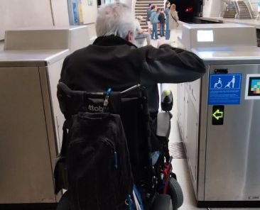 Persona usuaria de silla de ruedas pasando por una canceladora accesible en una estación de tren de Euskotren.