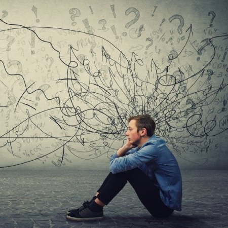 Persona sentada con gesto pensativo frente a una pared llena de flechas y símbolos caóticos que representan confusión mental y sobrecarga emocional.