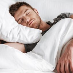 Persona durmiendo tranquilamente en la cama como representación del descanso saludable.