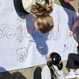 Niños y niñas dibujando juntos en una actividad educativa inclusiva al aire libre