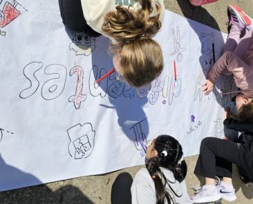 Niños y niñas dibujando juntos en una actividad educativa inclusiva al aire libre
