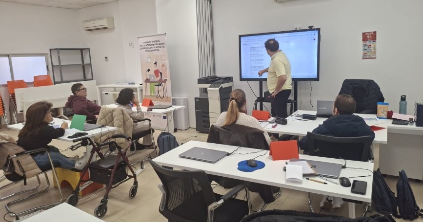 Personas con discapacidad participan en un curso de formación con docente explicando en pantalla digital