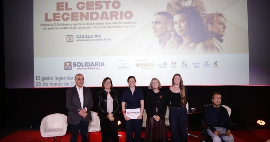Personas participantes en la presentación de la campaña X Solidaria “El gesto legendario” en un escenario con pantalla informativa al fondo