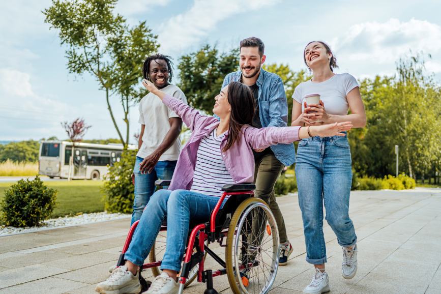 Personas voluntarias acompañando a una mujer en silla de ruedas durante una actividad de ocio inclusivo al aire libre