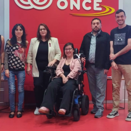 Grupo de participantes en la jornada de Federación ASEM sobre enfermedades neuromusculares en la sede de ONCE, con una mujer en silla de ruedas en el centro.