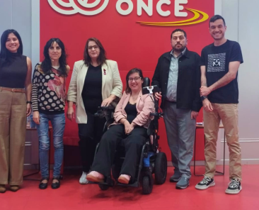 Grupo de participantes en la jornada de Federación ASEM sobre enfermedades neuromusculares en la sede de ONCE, con una mujer en silla de ruedas en el centro.