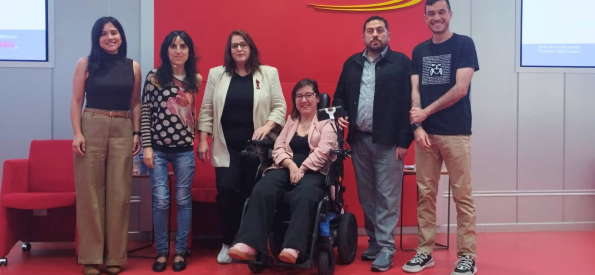 Grupo de participantes en la jornada de Federación ASEM sobre enfermedades neuromusculares en la sede de ONCE, con una mujer en silla de ruedas en el centro.