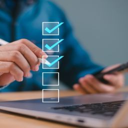 Persona completando un cuestionario online en ordenador y móvil con lista de verificación