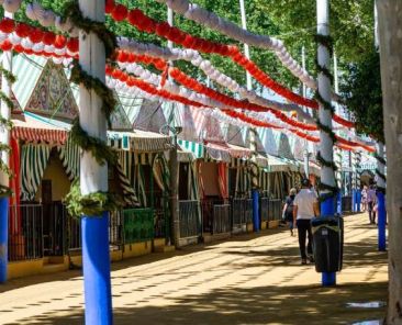 Paseo con casetas decoradas en una feria andaluza con personas transitando en un espacio público