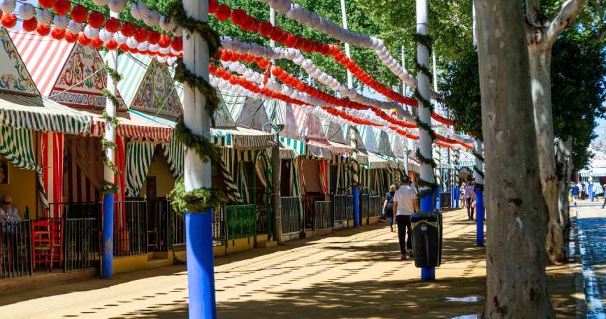 Paseo con casetas decoradas en una feria andaluza con personas transitando en un espacio público